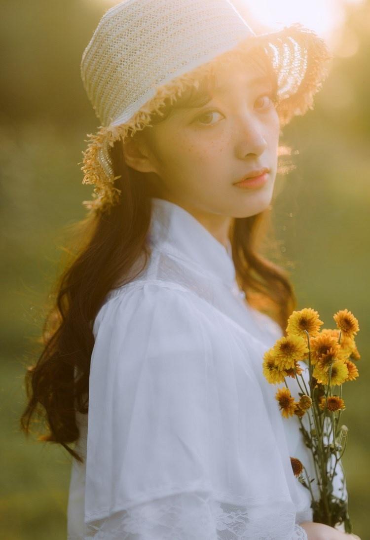 文藝美女潔白長(zhǎng)裙?jié)饷芫戆l(fā)手捧鮮花叢林寫(xiě)真圖片