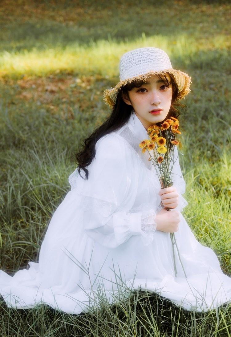 文藝美女潔白長(zhǎng)裙?jié)饷芫戆l(fā)手捧鮮花叢林寫(xiě)真圖片
