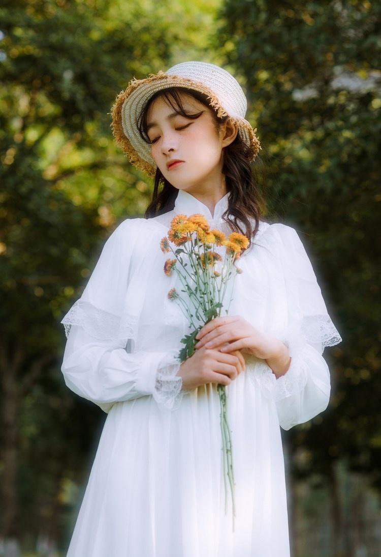 文藝美女潔白長(zhǎng)裙?jié)饷芫戆l(fā)手捧鮮花叢林寫(xiě)真圖片