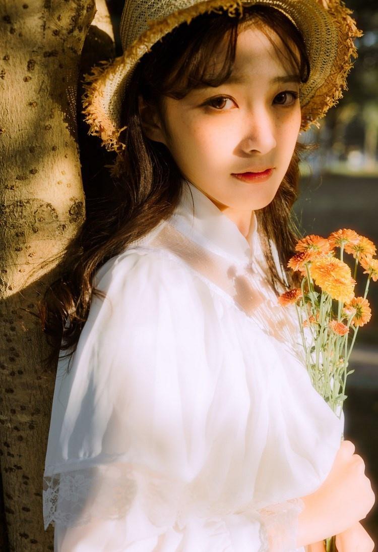 文藝美女潔白長(zhǎng)裙?jié)饷芫戆l(fā)手捧鮮花叢林寫(xiě)真圖片