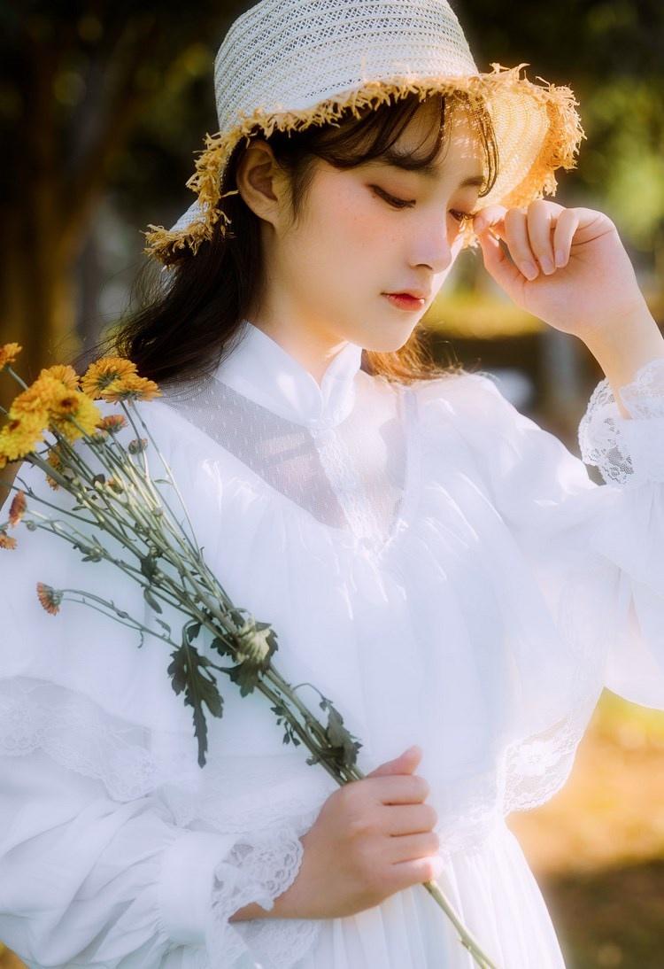文藝美女潔白長(zhǎng)裙?jié)饷芫戆l(fā)手捧鮮花叢林寫(xiě)真圖片