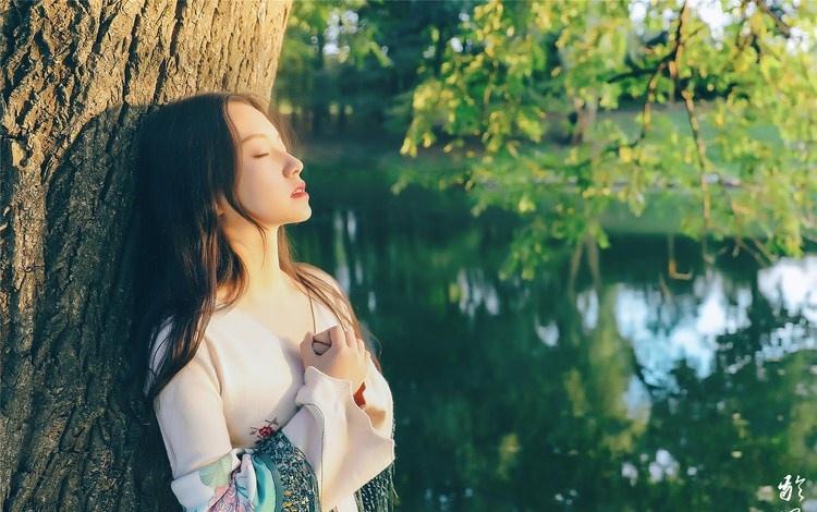 大樹下清純靈動美女手捧蘋果纖細身形圖片